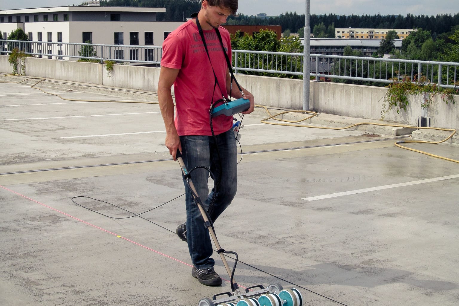 Messtechnik in der Hand eines Mannes zur Potentialfeldmessung auf dem Dach eines Parkhauses