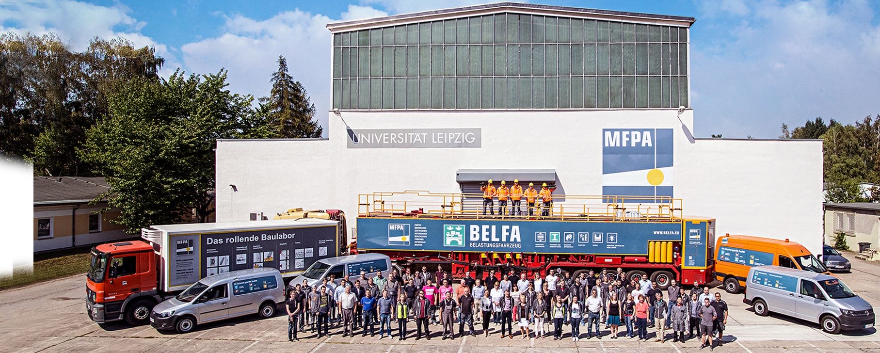 Gruppenbilder aller MFPA Mitarbeiter vor einer großen Prüfhalle und Firmenautos