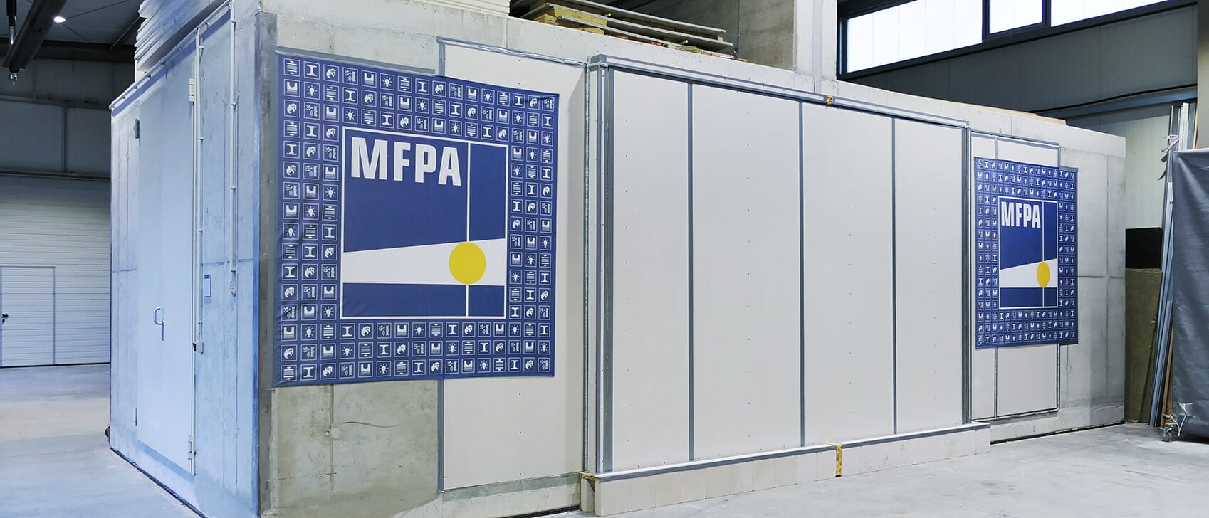 Außenansicht eines Längsschallleitungsprüfstands der MFPA aus Beton in einer Prüfhalle